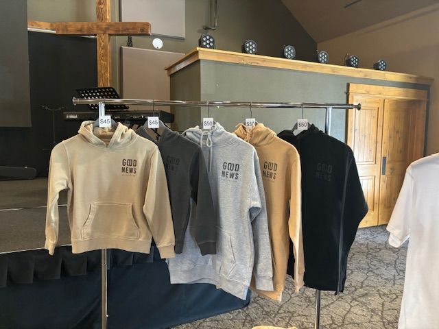 Printed hoodies in gray, charcoal and tan hanging on a clothing rack in a shop
