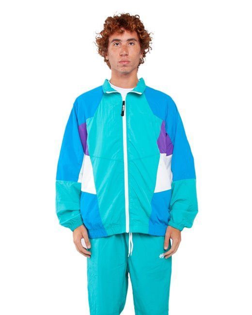 Man in a turquoise and purple nylon track jacket and pants