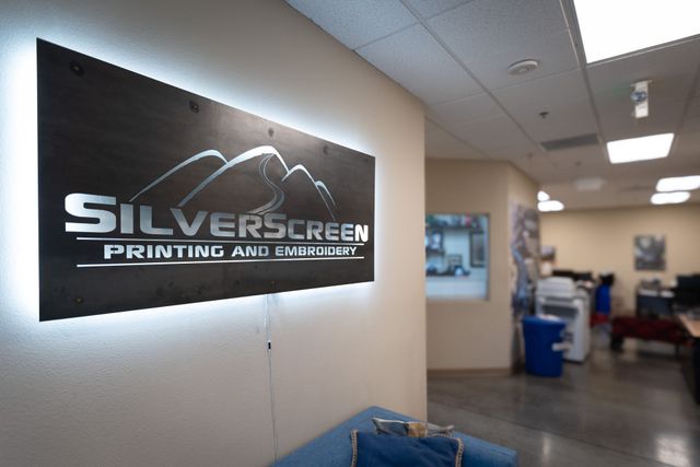 Backlit Silverscreen Printing and Embroidery logo sign on the wall of the front office